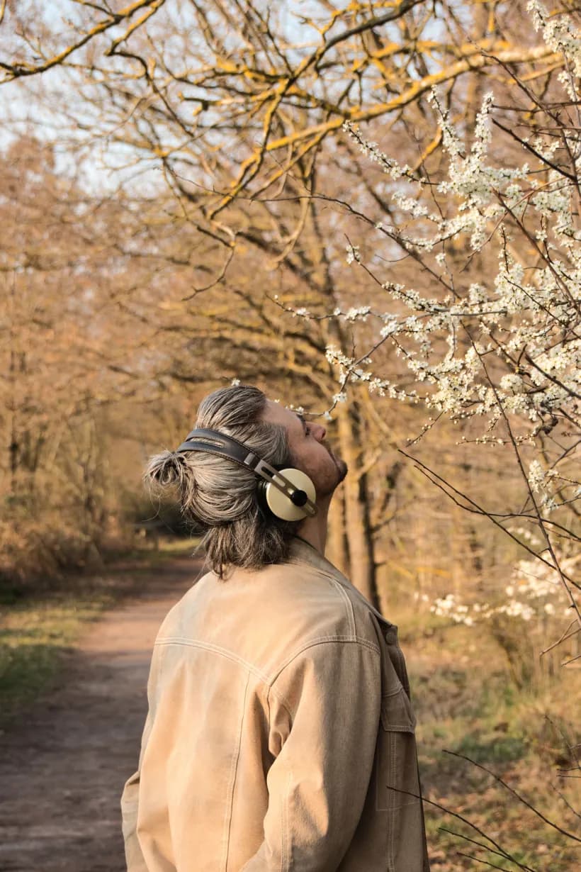 An adult taking a calm moment outdoors with headphones.
